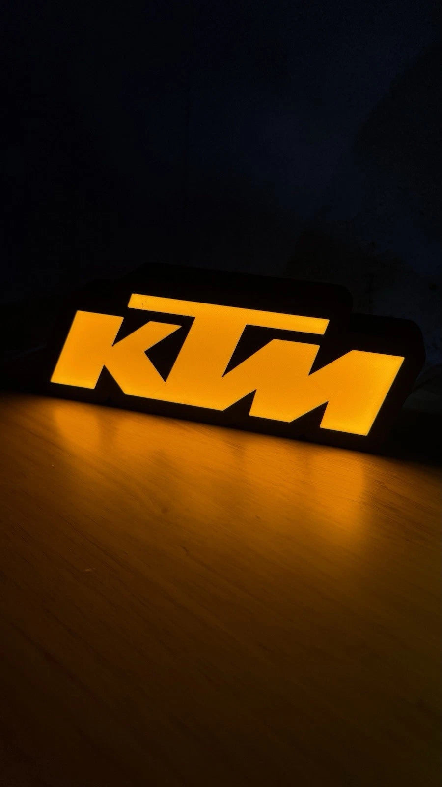 KTM inspired LED wall sign illuminated on a garage shelf